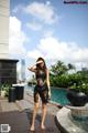 A woman in a black dress standing next to a pool.