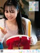 A woman sitting at a table with a red and yellow object.