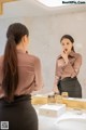 A woman standing in front of a mirror in a bathroom.