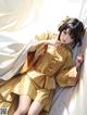A woman in a yellow kimono sitting on a bed.