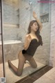 A woman in a black dress is posing in a bathroom.