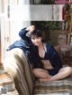 A woman sitting on top of a couch next to a window.