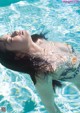 A woman floating in a swimming pool with her eyes closed.