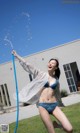 A woman in a blue bikini is playing with a hose.